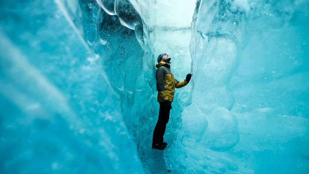 Guide leading a small group into a natural blue chamber on the original Vatnajökull ice caves tour at Breiðamerkurjökull, southeast Iceland